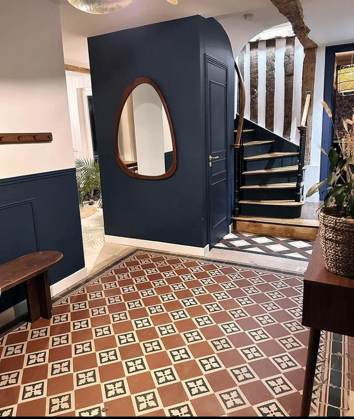 Entrée rénovée avec boiseries sombres et sol ancien conservé
